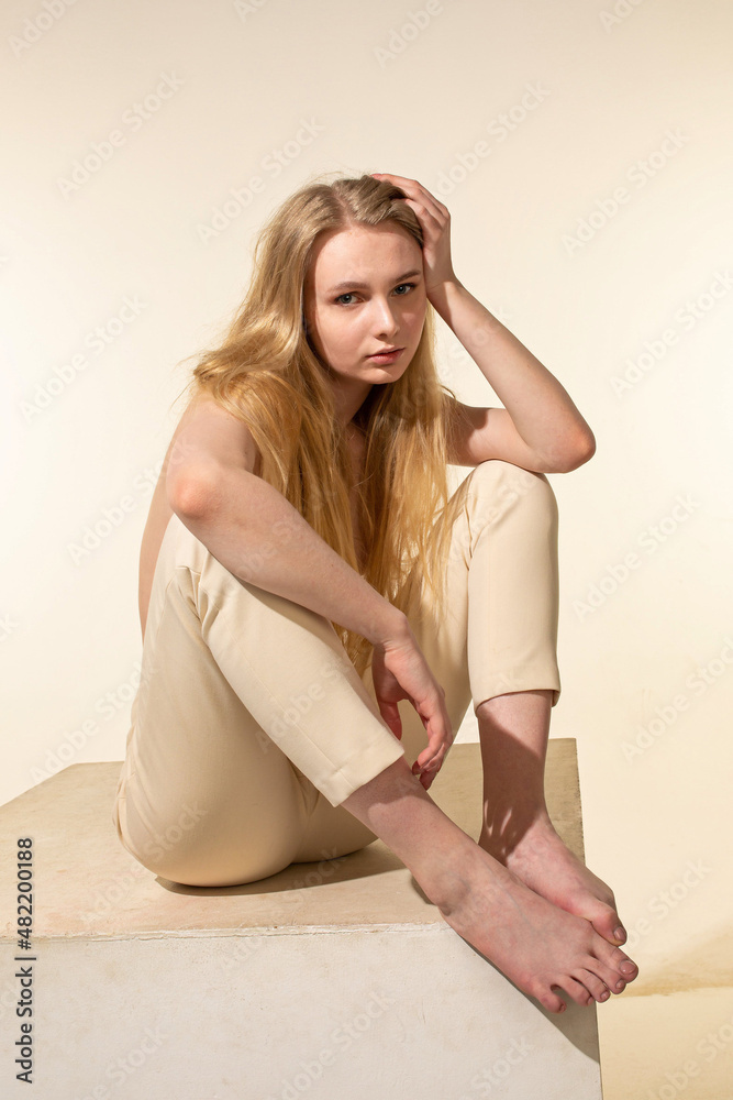 Naklejka premium European young woman with blonde hair isolated on beige with hand near the face