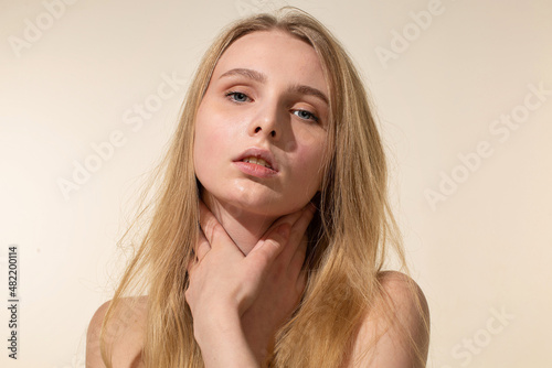 Young woman with blonde hair isolated on beige portrait