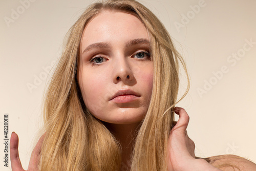 Portrait of young woman with blonde hair isolated on beige with nude make-up