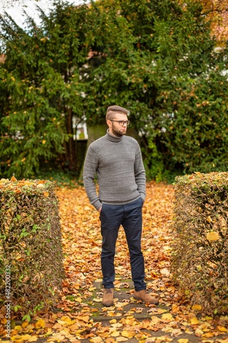 Bespectacled white young european man in park in fall