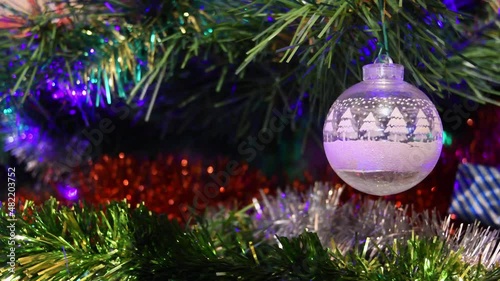 white transparent christmas ball in a fir tree with lights in the background