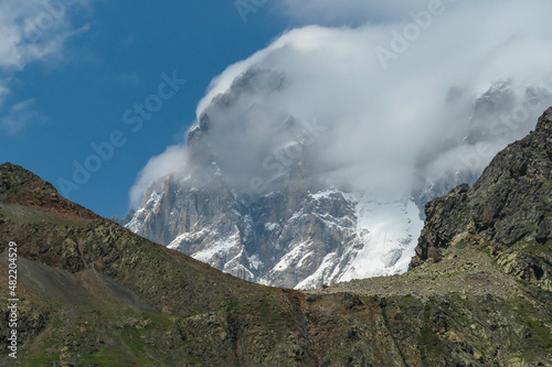 An amazing panoramic view on the mountain ridges near Mestia in the Greater Caucasus Mountain Range, Samegrelo-Upper Svaneti, Country of Georgia. The sharp peaks are covered in snow. Clouds arriving photo