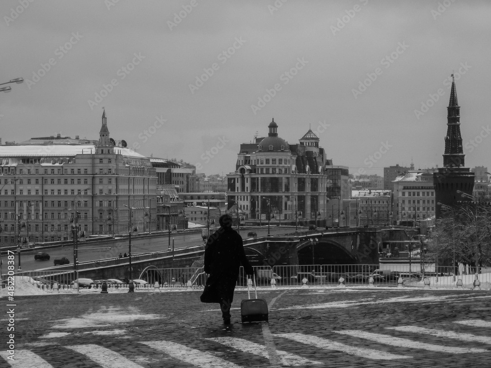A man walks across the square. An old photo. Snow is falling