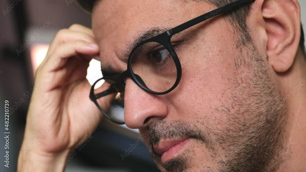 Close-up of a bearded man looking through glasses to computer monitor reading eyes moving Close-up of a bearded man looking through glasses to computer monitor reading eyes moving