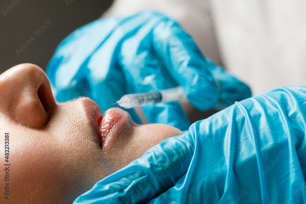 A woman makes lip shape correction in a cosmetology clinic. Lips injections, lip augmentation. A woman makes lip shape correction in a cosmetology clinic. Lips injections, lip augmentation.