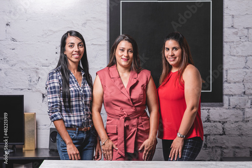 Fotografie Retrato horizontal tres mujeres latinas profesionales viendo a cámara