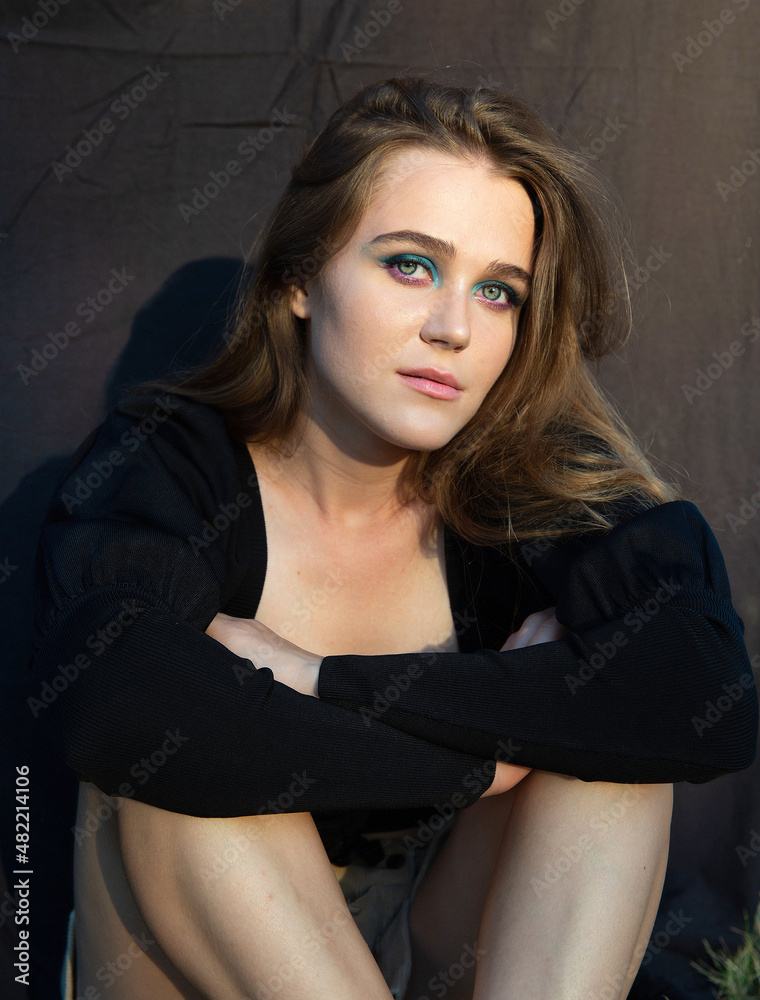 Sitting young woman with white skin isolated on dark brown with folded hands Sitting young woman with white skin isolated on dark brown with folded hands