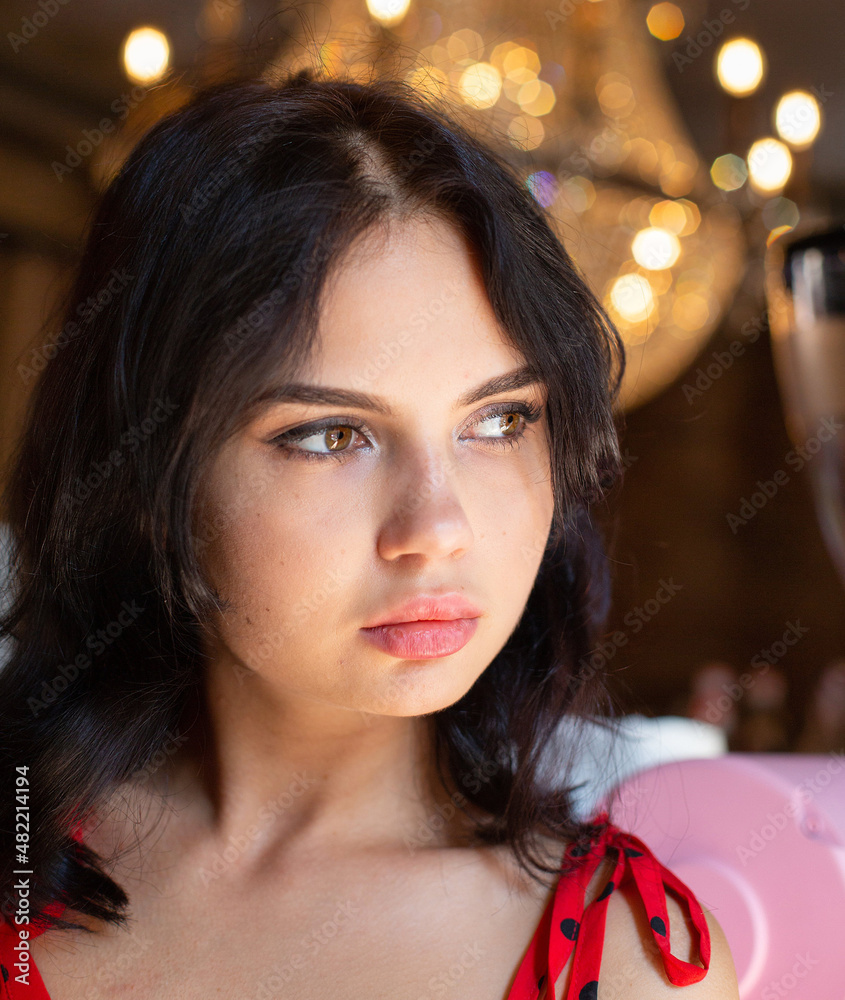 Fototapeta premium Portrait of young dark haired woman with white skin with lights behind with plump lips