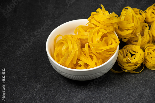 Raw fettuccine pasta in a plate isolated on dark background