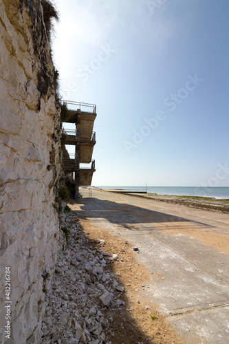 Chalk cliff with a concrete staircase casting a long shadow. Margate promenade