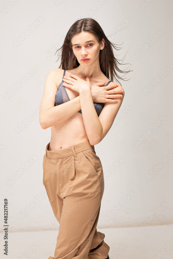 Young slim woman with dark straight hair isolated on beige with crossed arms on her chest Young slim woman with dark straight hair isolated on beige with crossed arms on her chest