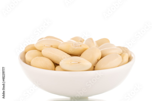 Lots of organic white beans in a white saucer, close-up, isolated on white.