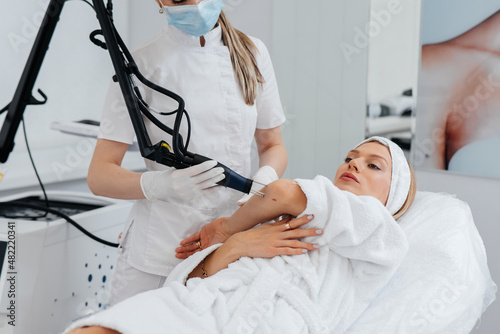 A young girl gets carbon peeling for the skin of her hands in a beauty salon. Laser pulses cleanse the skin. Hardware cosmetology. The process of photothermolysis  warming the skin.