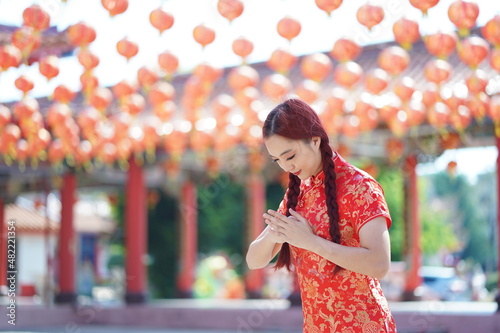 Happy Chinese new year. Asian woman wearing traditional cheongsam qipao dress with gesture of congratulation.