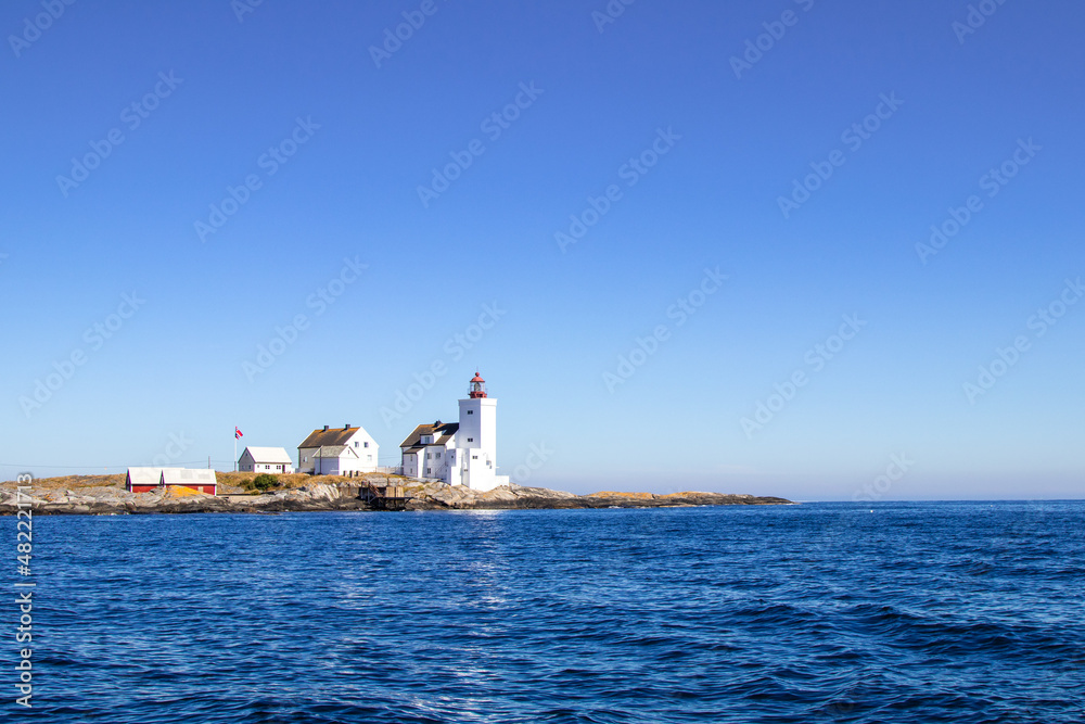 A lighthouse on an islet on the south coast of Norway. Sunlight, summer