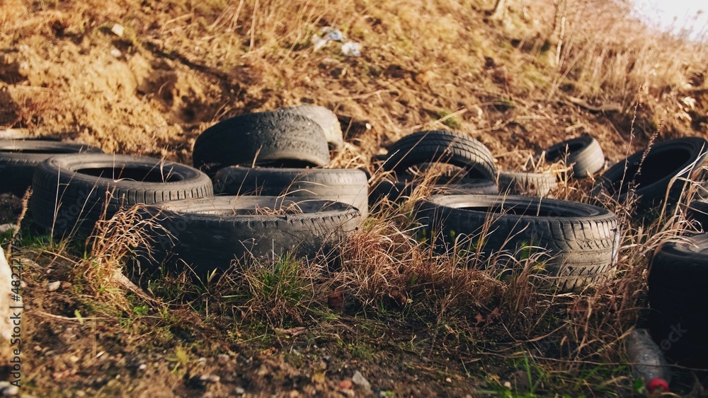 Obraz premium Used Worn Out Rubber Car Tires Dumped Illegally on Public Field 