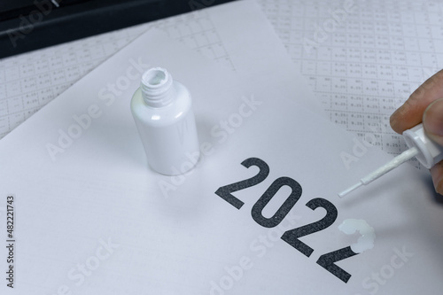Billede på lærred A man erases the year 2022 with correction fluid