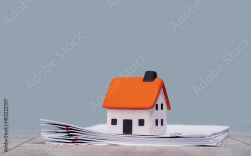 mortgage calculator or real estate business concept. Office desk with a white house on a pile of papers. Loan or insurance rate payments guidance support. Liability and risk photo