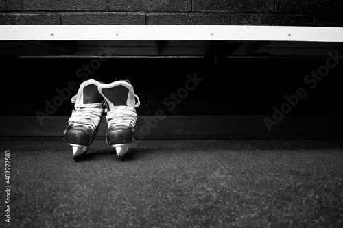 Hockey skates below bench in locker room in black and white with copy space