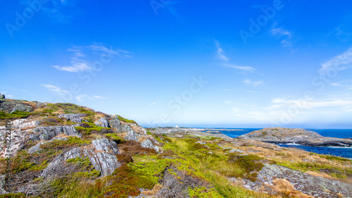 An island, islets and a lighthouse off in the distance. Clear skies, summer day