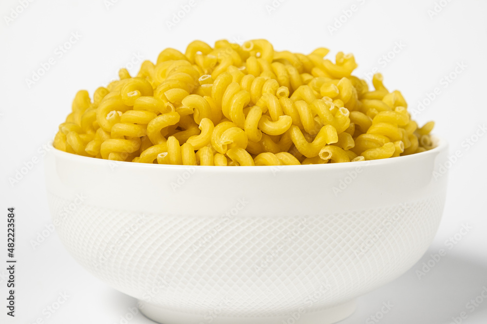 Raw Cavatappi Cellentani pasta in a plate isolated on yellow background Raw Cavatappi Cellentani pasta in a plate isolated on yellow background