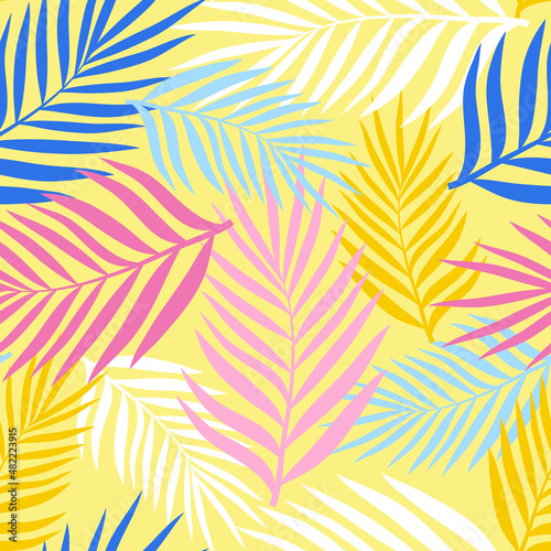 Palm leaves of different colors on a pale yellow background. Seamless pattern for any use.