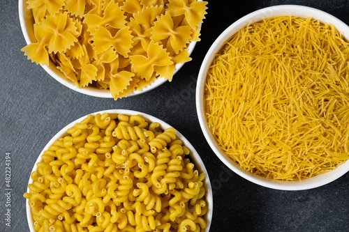 Close up of several types of dry pasta in a plate on dark background photo