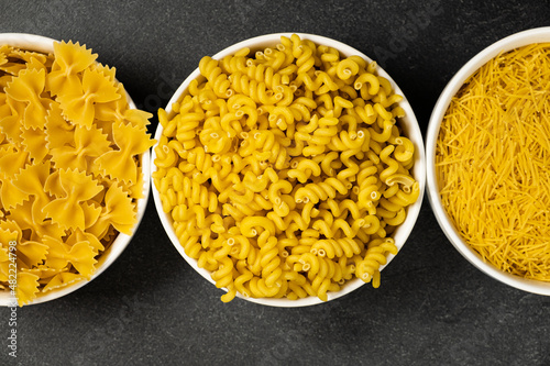 Close up of several types of dry pasta in a plate on dark background photo