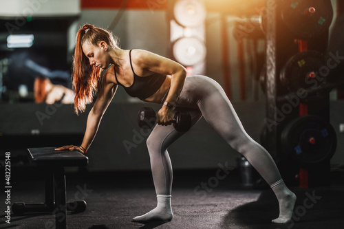 Fototapeta Naklejka Na Ścianę i Meble -  Muscular Woman Doing Training With Dumbell At The Gym