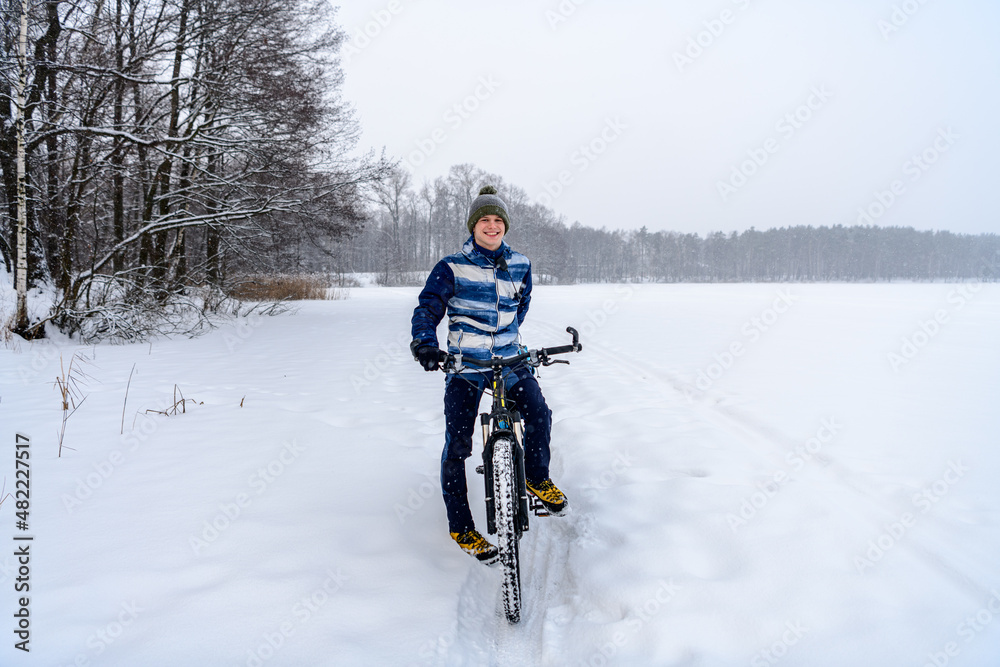 Russian bicyclist on winter lake with forest on background, Moscow Region