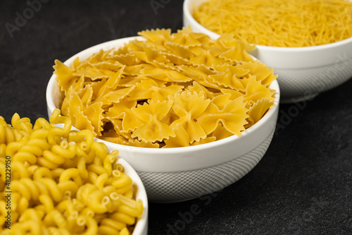 Close up of several types of dry pasta in a plate on dark background photo