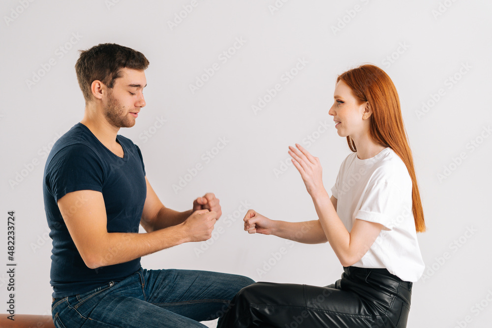 Studio shot of happy young man and woman playing rock scissors paper game on white isolated background. Concept of resolving conflicts in a peaceful and ecological way. Studio shot of happy young man and woman playing rock scissors paper game on white isolated background. Concept of resolving conflicts in a peaceful and ecological way.