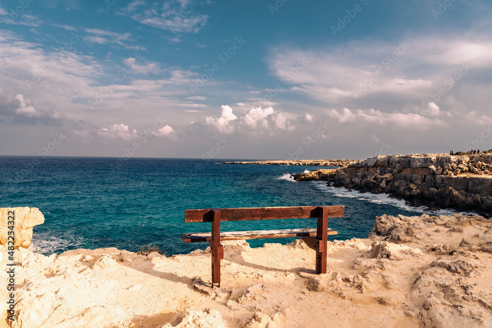 Wooden bench with a beautiful view of the sea and blue sky in the area of Cape Greco. Ayia Napa. Cyprus. 