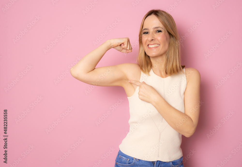 Positive joyful lady showing hand muscles standing isolated over pink background. Positive joyful lady showing hand muscles standing isolated over pink background.