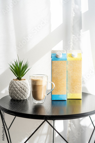 Coffee cup with coffee and alternative milk. Non-dairy milk made from potatoes, oats, almonds, rice, nuts, and soybeans has become commonplace in coffee shops. Milk packaging mockup. photo