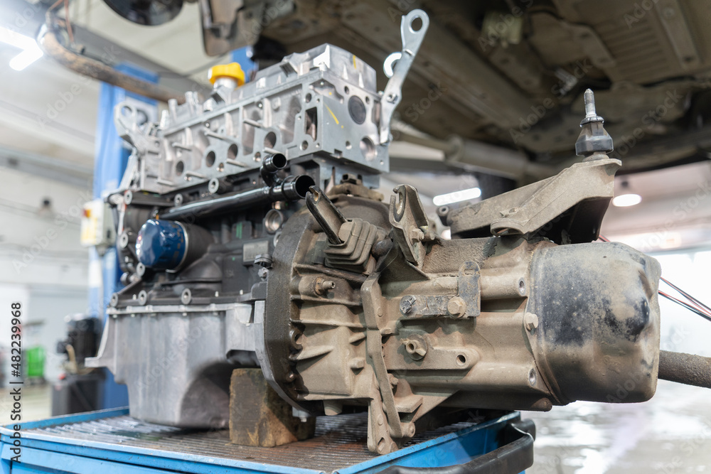 a gearbox mounted on a car engine stands on a workbench, under the car, close-up. selective focus