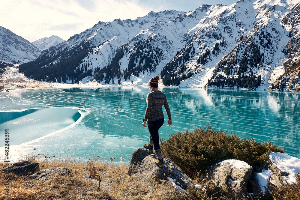 A woman walking near a frozen mountain lake