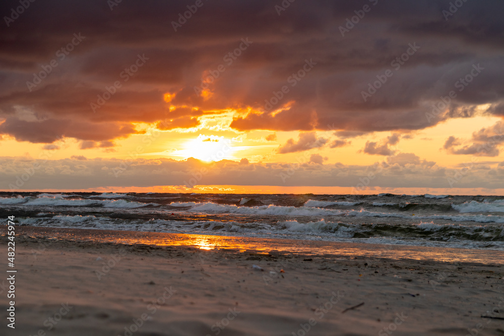 Sunset during cloudy summer day in Krynica Morska at the Baltic Sea. Beautiful view of sun behind clouds with light rays everywhere.