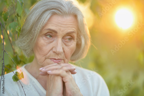 Portrait of sad senior beautiful woman posing in spring park