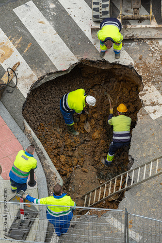 trabajadores arreglando una tubería en la ciudad y excavando un gran agujero para descubrir la conducción de agua