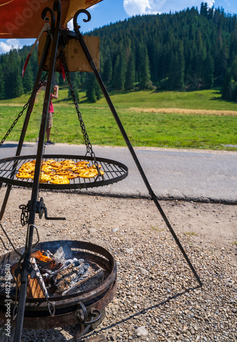 A smoked cheese made of salted sheep milk exclusively in the Tatra Mountains, Poland (oscypek) getting grilled on a barbecue. The cheese starts melting. Traditional mountain snack. Delicasy.