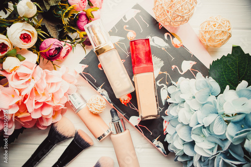 Foundations and flowers on white wooden background with notepad in spring photo