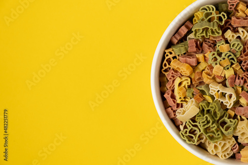 Pasta trottole tricolore wheat in a plate isolated on yellow background photo