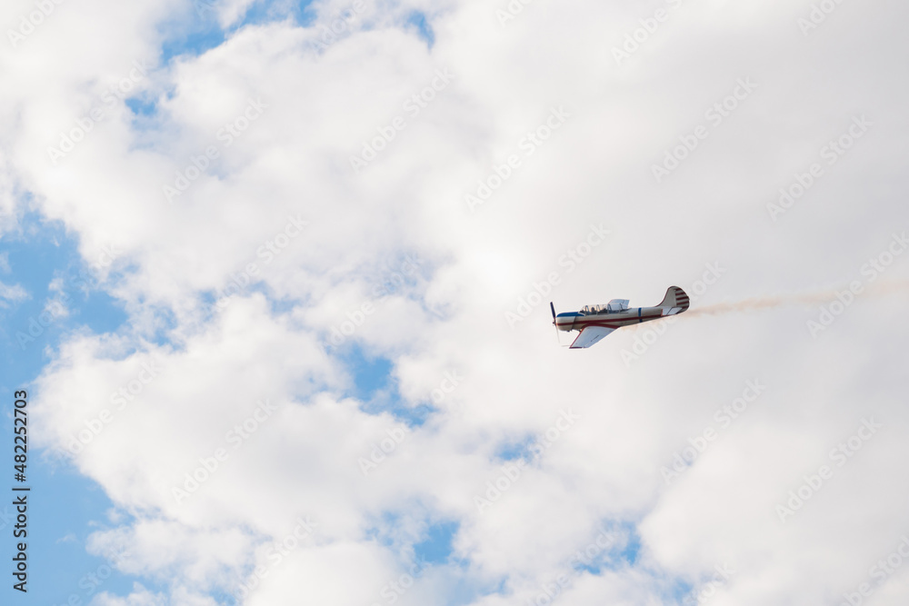 Small retro airplane, light aircraft flying in blue cloudy sky and doing stunts at Air Show. Performance, extreme, aerobatic and sport concept Small retro airplane, light aircraft flying in blue cloudy sky and doing stunts at Air Show. Performance, extreme, aerobatic and sport concept