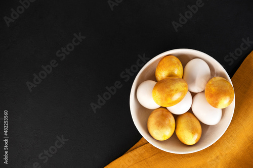 Yellow Easter eggs in a bowl on a dark background. Natural duing Easter eggs with turmeric powder in yellow color. photo