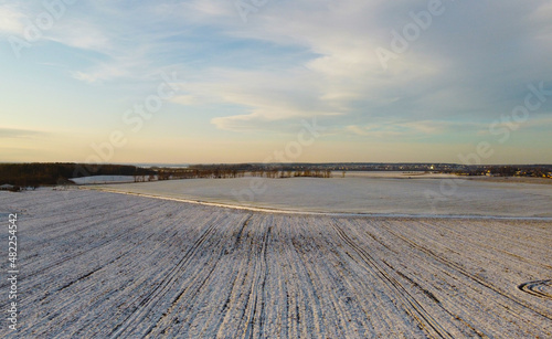Top view photo of a winter suburban landscape with snowy fields, meadows and forests