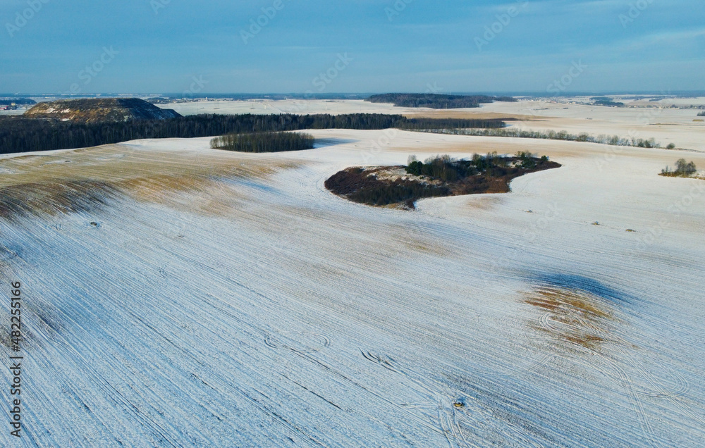 Fototapeta premium Top view photo of a winter suburban landscape with snowy fields, meadows and forests