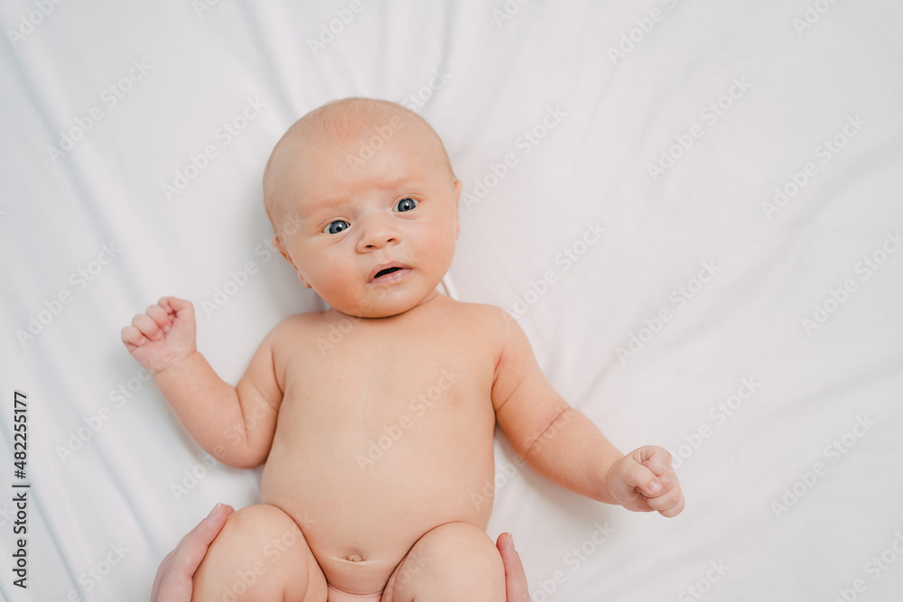 hands do exercises to baby on white sheet. exercise bike for a healthy tummy. hands do exercises to baby on white sheet. exercise bike for a healthy tummy.