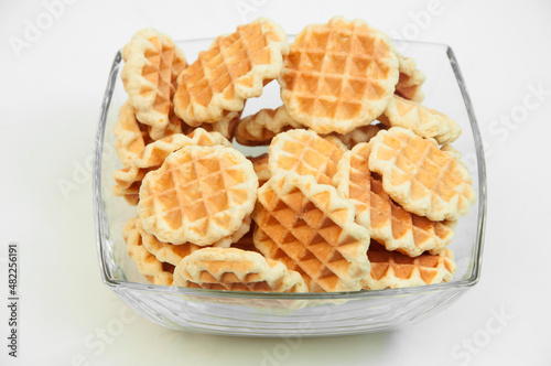 Belgian waffles in a glass bowl. holiday cookies on a white background. fresh baking concept. sweet desserts on a light texture