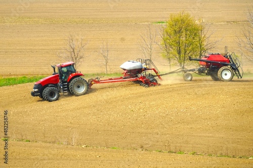 Farmer with tractor fertilizing crops at field
